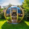 garden pods - photo of a garden pod with glass walls, seater and table in a backgarden.