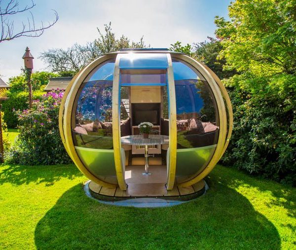 garden pods - photo of a garden pod with glass walls, seater and table in a backgarden.